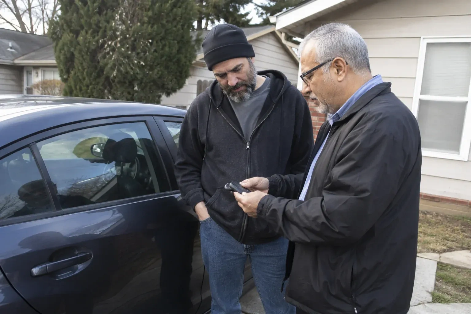 Two adults discussing a key fob beside a parked car. — Car Lockout Service, Markham