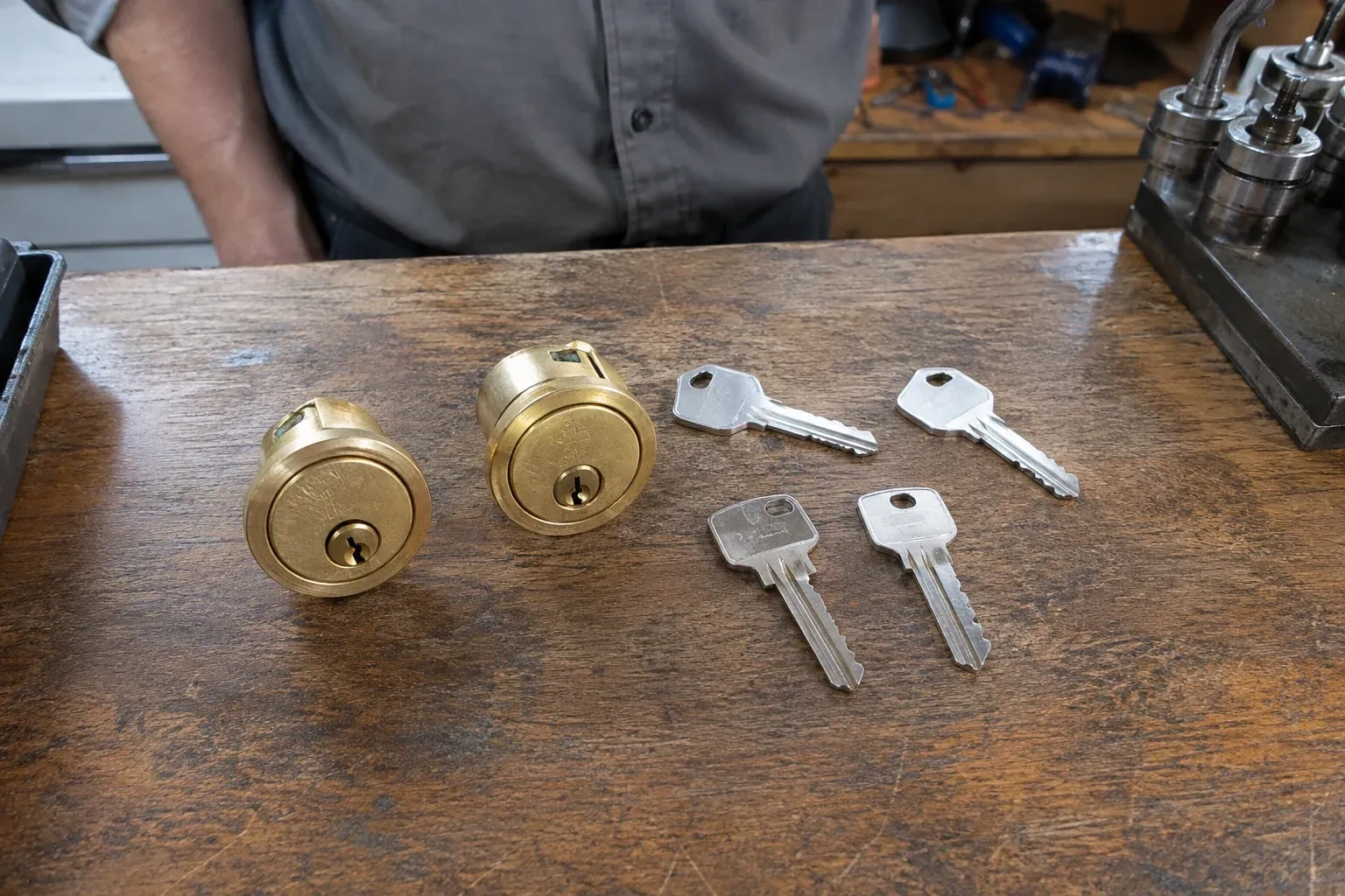 Two detached brass lock cylinders and four house keys on a wooden counter. — Lock Rekeying, Markham