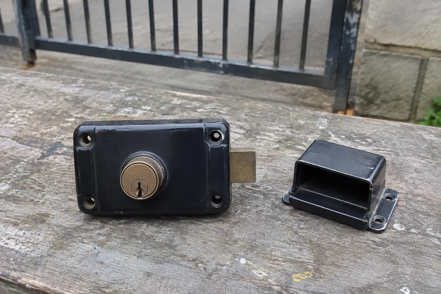 Detached rim gate lock and separate box keeper on an outdoor workbench. — Gate & Building Entry Locks, Markham